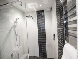 A bathroom shower area with white and black tiled walls and a glass shower screen at Two Bare Feet Rose near Perranporth