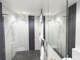 A walk in shower with glass screen white and black tiles and a towel rack at Two Bare Feet Rose near Perranporth