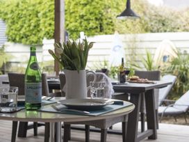 An outdoor dining area with tables set with plates glasses and a bottle of water at Two Bare Feet in Rose near Perranporth