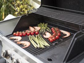 An outdoor grill with shrimp asparagus and cherry tomatoes on the grate at Two Bare Feet in Rose near Perranporth
