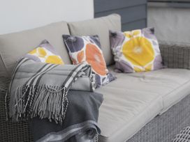A wicker sofa with cushions and folded blankets on the armrest at Two Bare Feet in Rose near Perranporth