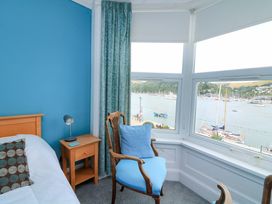 A bedroom with a bed and a chair overlooking the harbor at Castleview Apartment, 21 South Embankment, Dartmouth