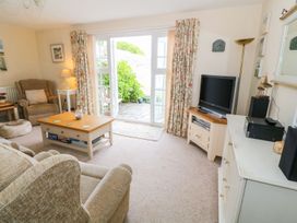 A living room with a sofa, armchair, coffee table and television at The Cottage On The Green in Porthmadog