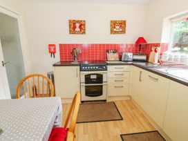 A kitchen with oven and dining table at The Cottage On The Green in Porthmadog