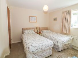 A bedroom with two single beds and a nightstand at The Cottage On The Green in Porthmadog