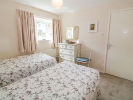 A bedroom with two beds and a dresser at The Cottage On The Green in Porthmadog