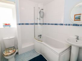 A bathroom with a bathtub, shower, toilet, and sink at The Cottage On The Green in Porthmadog