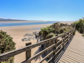 A pathway leading to a sandy beach with rocks and water at The Cottage On The Green in Porthmadog