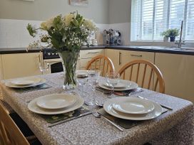 A dining table set with plates and a flower vase at The Cottage On The Green Borth-Y-Gest