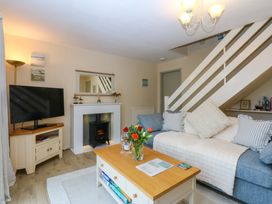 A living room with a television, sofa, and coffee table at The Cottage On The Green in Borth-Y-Gest