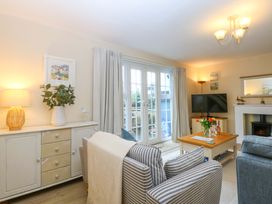 A living room with a sofa, television, and vase on the table at The Cottage On The Green in Borth-Y-Gest