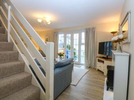 A living room with a staircase, couch, and television at The Cottage On The Green in Borth-Y-Gest