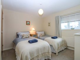 A bedroom with two beds and a bedside table at The Cottage On The Green in Borth-Y-Gest