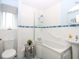 A bathroom with a bathtub, toilet, sink and shower at The Cottage On The Green in Borth-Y-Gest