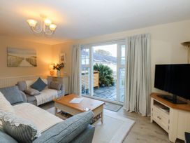 A living room with a sofa, television, and coffee table at The Cottage On The Green in Borth-Y-Gest