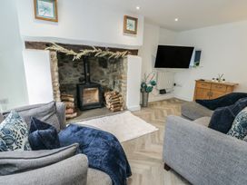 A living room with a fireplace and television at Rhows in Niwbwrch (Newborough)