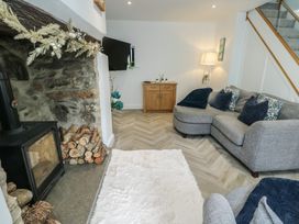A living room with a fireplace and sofa at Rhows in Niwbwrch (Newborough)