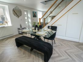 A dining room with a glass table and black chairs at Rhows Niwbwrch (Newborough)