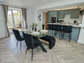 A kitchen with a dining area including a glass table and chairs at Rhows in Niwbwrch (Newborough)