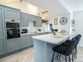 A kitchen with cabinets and bar stools at Rhows in Niwbwrch (Newborough)