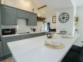A kitchen with cabinets, countertop, sink, and dishes at Rhows, Niwbwrch (Newborough)