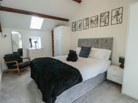A bedroom with a bed and armchair at Rhows in Niwbwrch (Newborough)