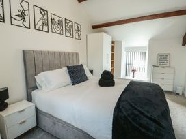 A bedroom with a bed and nightstand at Rhows in Niwbwrch (Newborough)