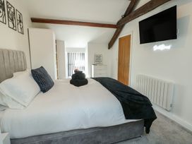 A bedroom with a bed and television at Rhows in Niwbwrch (Newborough)