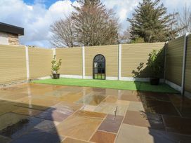 A garden with a stone patio and plants at Rhows in Niwbwrch (Newborough)