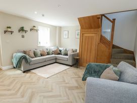 A living room with a sofa and stairs at Hen Siop Niwbwrch (Newborough)
