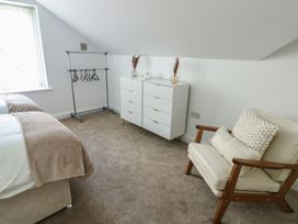 A bedroom with a bed, clothes rack, drawer unit, and chair at Hen Siop, Niwbwrch (Newborough)