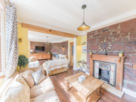 A living room with sofas a wooden coffee table a fireplace and a TV on a cabinet at 1 Cleator Gate in Cleator