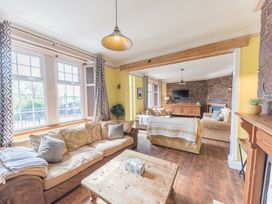 A living room with multiple sofas a wooden coffee table and a television on an ornate wooden cabinet at 1 Cleator Gate in Cleator