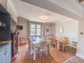 A dining room with two wooden tables set with plates and glasses a fireplace and a window at 1 Cleator Gate in Cleator