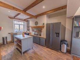 A kitchen with wooden beams on the ceiling a large refrigerator an island and shelves with books at 1 Cleator Gate in Cleator