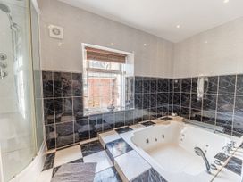 A bathroom with a built in bathtub a shower enclosure and a window at 1 Cleator Gate in Cleator