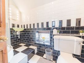 A bathroom with a toilet a glass sink a small window and black and white tiled walls and floor at 1 Cleator Gate in Cleator