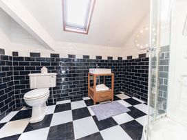 A bathroom with a toilet, a wooden vanity with a sink, a checkered black and white tiled floor, and a skylight at 1 Cleator Gate in Cleator