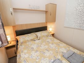 A bedroom with a bed and bedside table at Cate’s Cozy Cabin High Hesket near Lazonby
