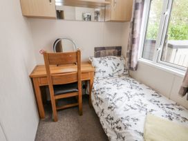 A bedroom with a bed and desk at Cate’s Cozy Cabin High Hesket near Lazonby