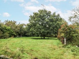 A garden with a tree and chairs at Meadow Island Caravan