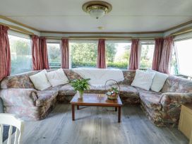 A living room with a sofa and table at Meadow Island Caravan in Penygroes