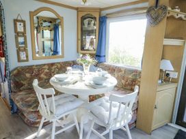 A dining room with a round table and chairs at Meadow Island Caravan Penygroes