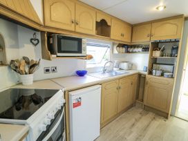 A kitchen with cabinets, sink, and appliances at Meadow Island Caravan Penygroes