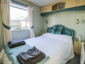 A bedroom with a bed and curtains at Meadow Island Caravan in Penygroes