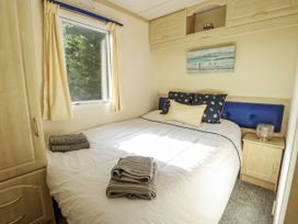 A bedroom with a bed and a window at Meadow Island Caravan in Penygroes