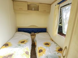 A bedroom with two beds and a window at Meadow Island Caravan Penygroes