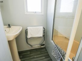 A bathroom with sink, shower and towel rack at Meadow Island Caravan Penygroes