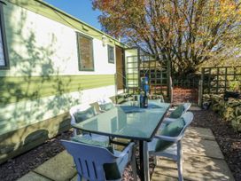 An outdoor seating area with a table and chairs at Meadow Island Caravan Penygroes