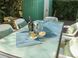 An outdoor seating area with a table set with a wine bottle and snacks at Meadow Island Caravan Penygroes